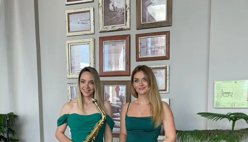 Saxophone and vocal duo in green dresses ready to play at an event in Dubai